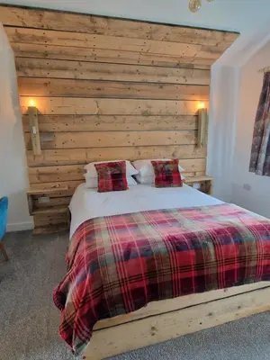 a bedroom with a bed with a wooden wall at Byre 1 InThePark in Stirling