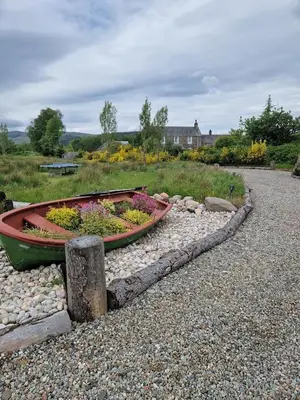 a boat with flowers in it sitting on the rocks at Byre 1 InThePark in Stirling