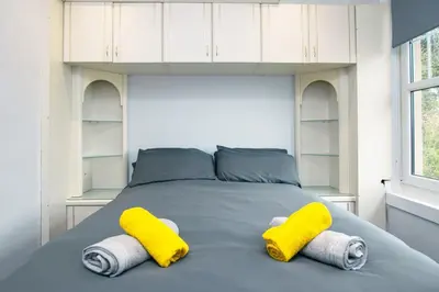 a bedroom with a bed with yellow and white towels at Cosy & Central 2BD Apartment Milngavie, Glasgow in Milngavie