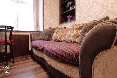 a couch sitting in a living room next to a window at The Wee Nook Crieff - 1-bed with garden :) in Crieff