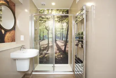 a bathroom with a shower with a sink and a mirror at Braidhaugh Holiday Lodge and Glamping Park in Crieff