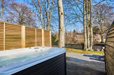 a hot tub in a backyard with a fence at Braidhaugh Holiday Lodge and Glamping Park in Crieff