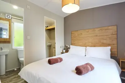 a bedroom with a large white bed with two towels at Braidhaugh Holiday Lodge and Glamping Park in Crieff