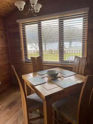 a wooden dining room table with chairs and a bowl on it at Cozy Loch Lomond Lodge 27, Rowardennan in Rowardennan