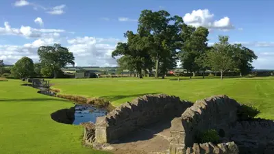 an old stone wall on a golf course at Silver Birch Lodge in Auchterarder