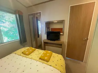 a bedroom with a bed with yellow sheets and a television at Silver Birch Lodge in Auchterarder