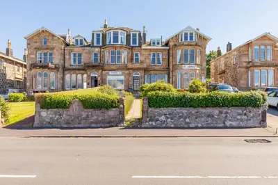 a large building with bushes in front of a street at The Ardyne Guest House in Rothesay