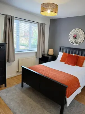 a bedroom with a bed with orange pillows and a window at Urban Escape Glasgow Green Free Parking 20min walk to City Center in Glasgow