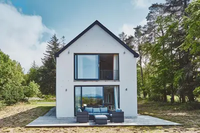 a small white house with a large window at Beach House in Pennygown