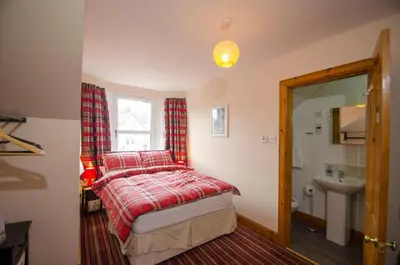 a bedroom with a bed and a window and a sink at Knight's Rest Guest House in Airdrie