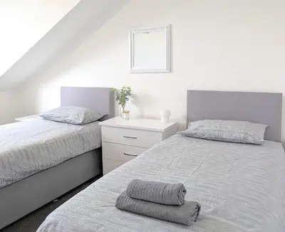 a bedroom with two beds and a dresser and a bedskirts at Campbeltown Loch in Campbeltown