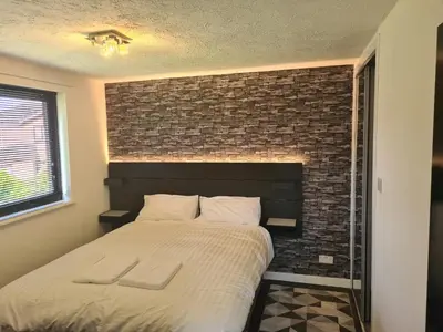 a bedroom with a bed with a brick wall at Travel Host 3 BEDROOM HOUSE WITH FREE PARKING in Nitshill