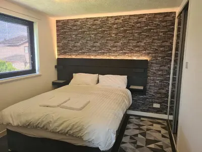 a bedroom with a large bed with a brick wall at Travel Host 3 BEDROOM HOUSE WITH FREE PARKING in Nitshill