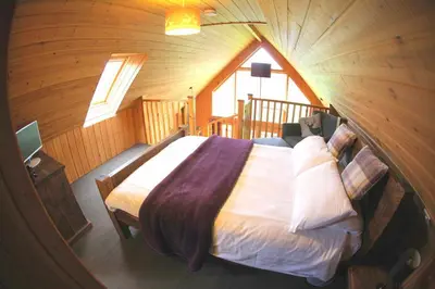 a bedroom with a bed in a wooden cabin at Loch Aweside Forest Cabins in Dalavich