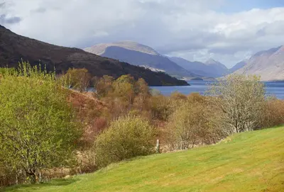 a view of a lake with mountains and a field at Port na Mine in Bonawe