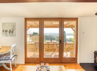 a room with a sliding glass door with a table at The Old Barn - cottage with spectacular lake view in Port of Menteith