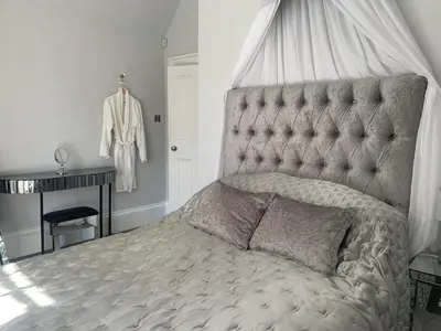 a bedroom with a bed with a tufted headboard at Pollokshields Burgh Hall Lodge Houses in Glasgow