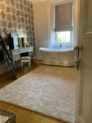 a bath tub in a bathroom with a window and a rug at Pollokshields Burgh Hall Lodge Houses in Glasgow