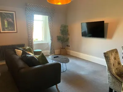 a living room with a couch and a tv at Pollokshields Burgh Hall Lodge Houses in Glasgow