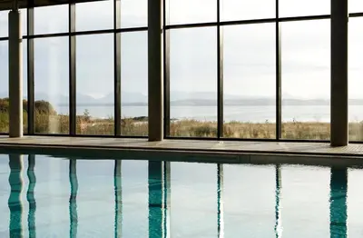 a swimming pool with windows looking out at the water at Isle Of Mull Hotel and Spa in Craignure