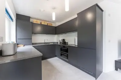 a large kitchen with black cabinets and appliances at Mhuilinn Apartment in Stirling
