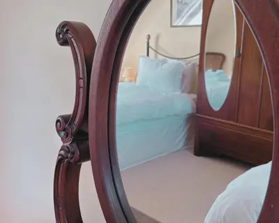 a bedroom with a bed and a mirror at Blaeberry Cottage in Killean