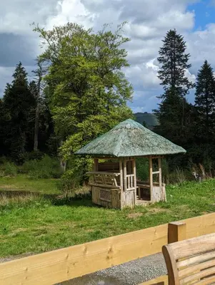 a gazebo with a grass roof in a field at The Castleton 20 in Ardentinny