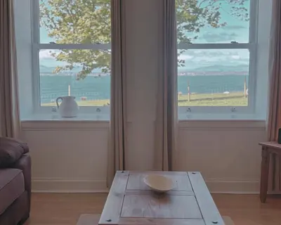 a living room with a table in front of a window at Primrose Cottage in Killean
