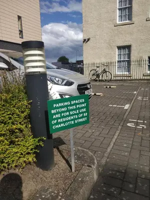 a sign in a parking lot next to a car at Glasgow city Charlotte service Aparments in Glasgow
