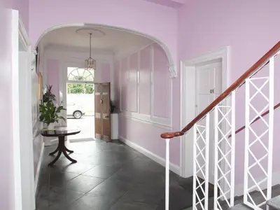 a hallway with pink walls and a staircase with a table at Glasgow city Charlotte service Aparments in Glasgow