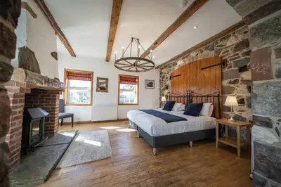a bedroom with a bed and a stone wall at Oak Tree Inn in Balmaha