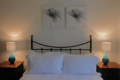a bedroom with a bed with white pillows and two lamps at Harebell Cottage in Killean