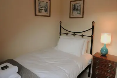 a bedroom with a white bed with a lamp on a dresser at Harebell Cottage in Killean