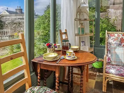 a table with cups and saucers on it in a room at Ivy Cottage in Crieff