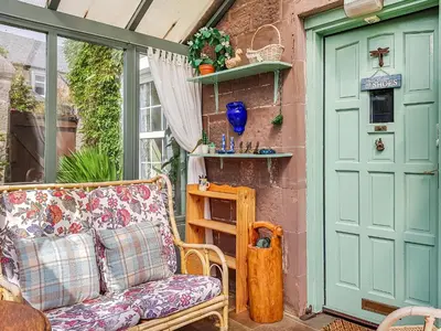 a porch with a couch and a green door at Ivy Cottage in Crieff