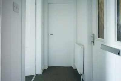 a hallway with white walls and a door at Meadow Apartment in Dumbarton