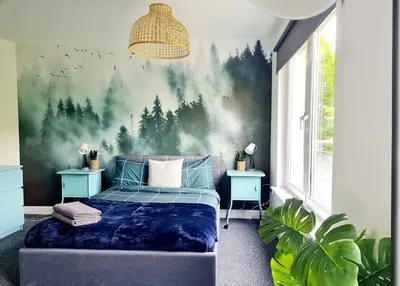 a bedroom with a bed with a forest mural on the wall at Spacious 5bed house, FREE parking, NO PARTY ! in Glasgow