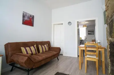 a living room with a brown couch and a table at 1 BDR House By Caledonia Luxe Stays Short Lets & Serviced Accommodation Lanark in Douglas