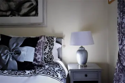 a bedroom with a bed with a lamp on a table at Loch Lomond Unique Selfcontained bed+bathroom in Alexandria