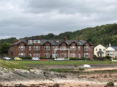 a large brick building with cars parked in front of it at 4 Kames Bay in Millport