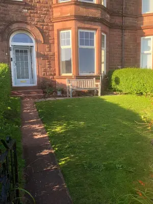 a house with a bench in front of a yard at 4 Kames Bay in Millport