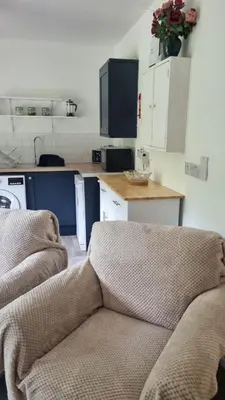 a living room with a couch and a kitchen at Killean Farmhouse Cottages in Auchnangoul