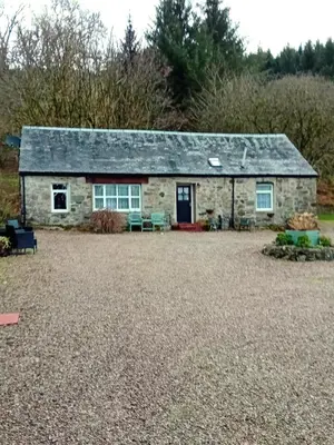 a stone cottage in the middle of a yard at Killean Farmhouse Cottages in Auchnangoul