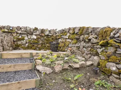 a stone wall with a bunch of rocks and flowers at Balvicar Beag in Oban
