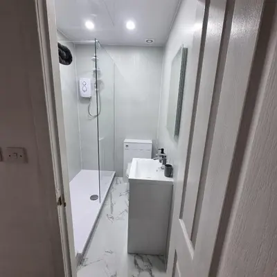 a white bathroom with a shower and a sink at Cove Bay 1 Bed Flat in Largs