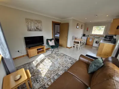 a living room with a couch and a kitchen at Kings Reach - Crinan Cottage in Lochgilphead