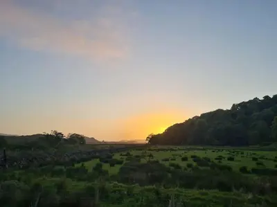 a field with the sun setting in the background at Kings Reach - Crinan Cottage in Lochgilphead