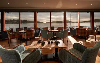 a restaurant with tables and chairs and a view of the water at Oban Bay Hotel in Oban