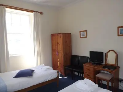 a bedroom with two beds and a desk and a mirror at Palace Hotel - Small Hotel in Oban