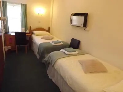 a hotel room with two beds and a tv at Palace Hotel - Small Hotel in Oban